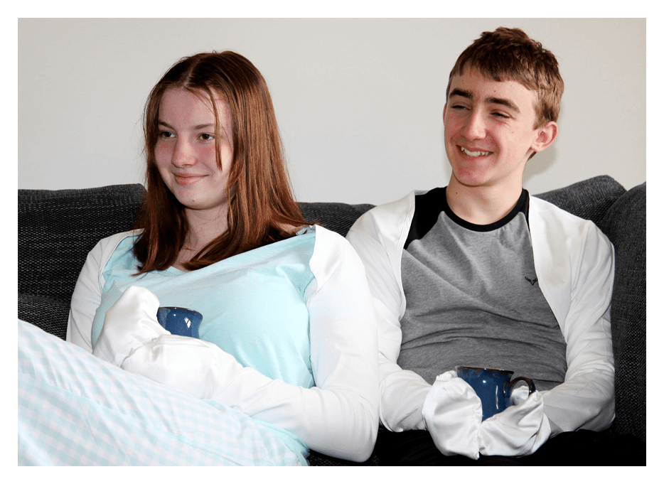 Two young adults wearing PJs and ScratchSleeves holding coffee mugs