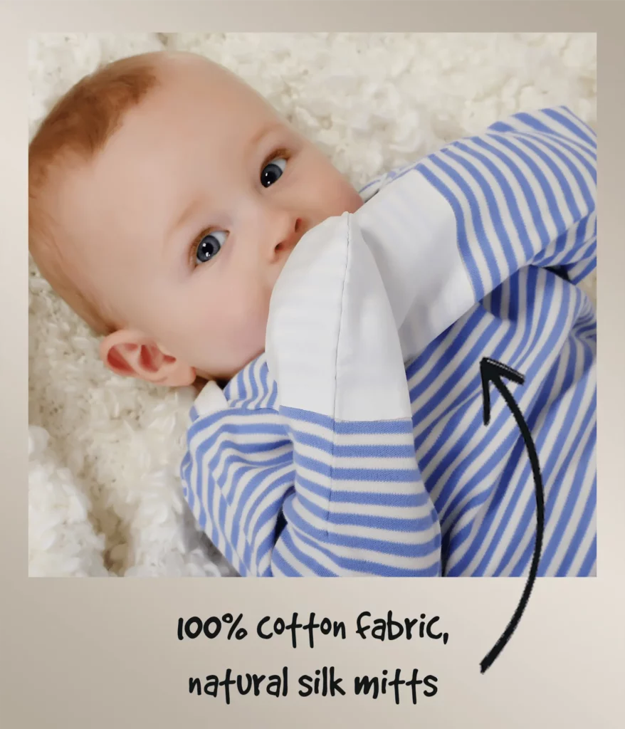 Baby boy wearing blue and white striped ScratchSleeves PJs with white integrated silk mittens. Annotated to show how the mitts work.