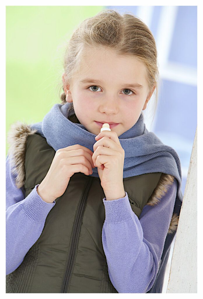 Girl applying lip balm from stick type lip salve