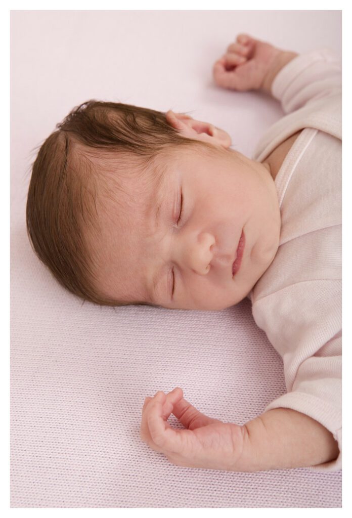 Baby girl sleeping soundly on her back