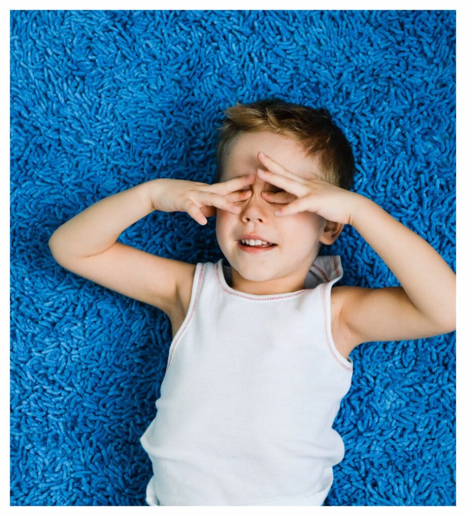 young boy in white vest trying unsuccessfully to sleep on a hot summer night.