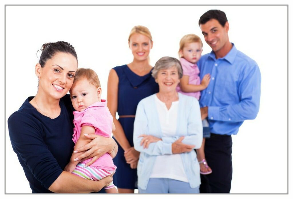 Mother holding young child in foreground. In the back ground is her support network of family and friends.