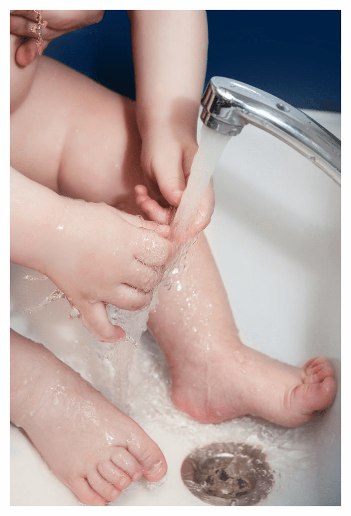 Close-up of small child playing with water from a running tap
