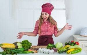 Teenage girl hamming it up looking worktop covered with colourful healthy food rich in eczema friendly vitamins and minerals