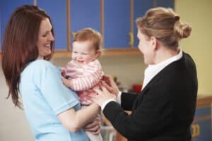 Mother dropping child at nursery. The mother is wearing a black suit jacket, which may be unwise!