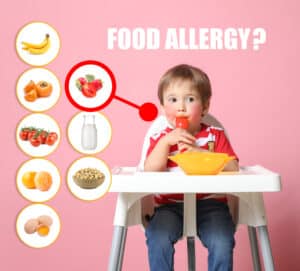 Toddler boy in high chair with various allergic foods. Strawberries, a common eczema trigger, are high-lighted