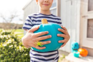 Young boy holding a painted painted teal signifying allergy friendly trick or treat location